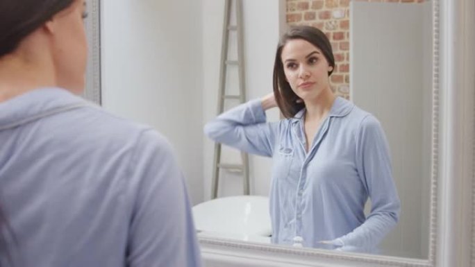 穿着睡衣在现代浴室里刷牙的女人，镜子里的映像