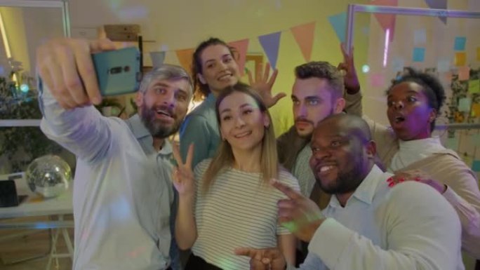 快乐的商人使用智能手机相机在公司聚会上自拍