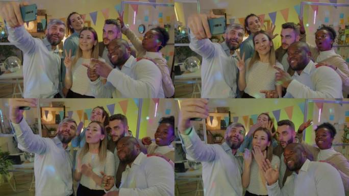 快乐的商人使用智能手机相机在公司聚会上自拍