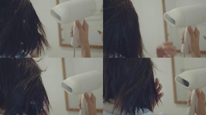 亚洲女性用吹风机吹干头发。