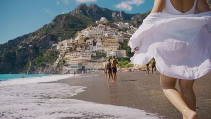 穿着白衬衫的SLO MO女人沿着著名的海滩Positano Spiaggia散步