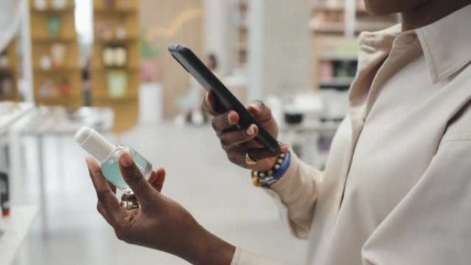 年轻女性购物者手中的智能手机和带有护肤品的瓶子