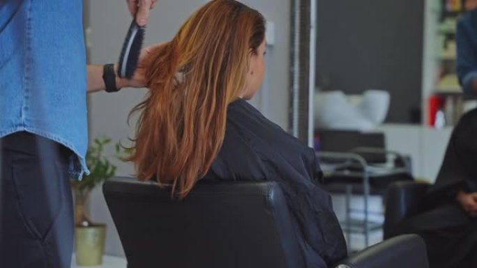 发型师在沙龙梳理女性顾客的头发