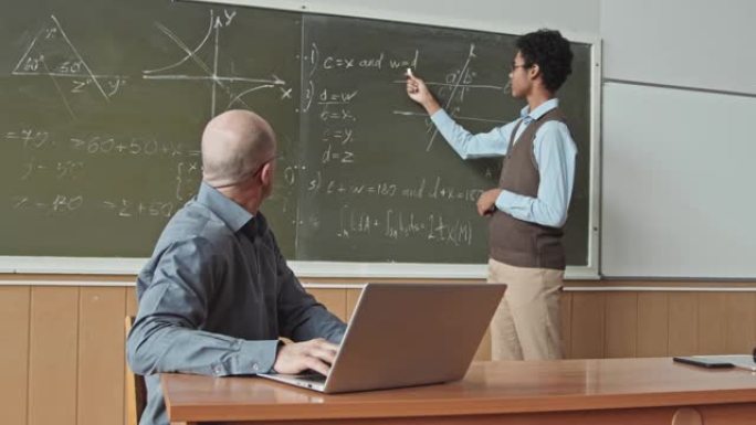 混合种族学生在黑板上解决几何问题