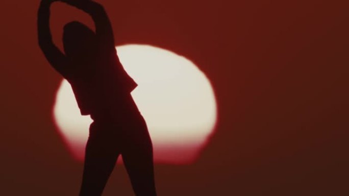 侧影中的SLO MO LS女人在日落时做热身运动