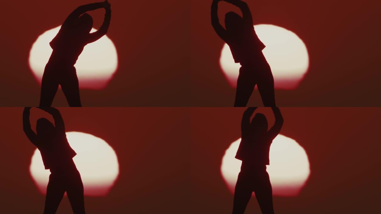 侧影中的SLO MO LS女人在日落时做热身运动