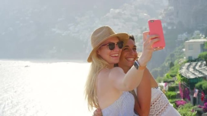 两个快乐的朋友在意大利度假时在美丽的景色前用手机自拍
