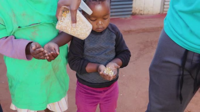 非洲的贫困。三个饥饿的非洲黑人儿童在慈善组织分发玉米时伸出双手