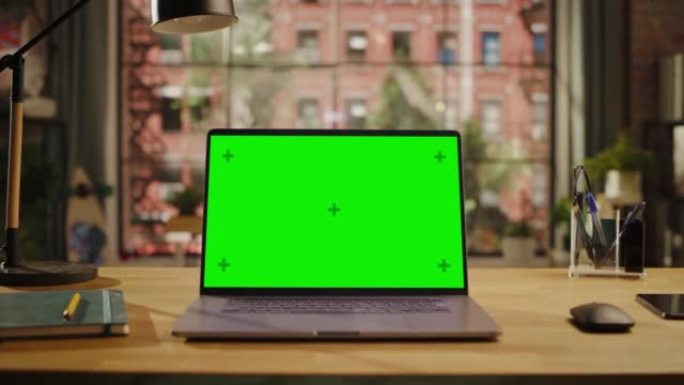 笔记本电脑显示屏，带有模拟绿屏，站在客厅的木制桌子上，笔记本电脑和智能手机。家里或创意阁楼办公室的色