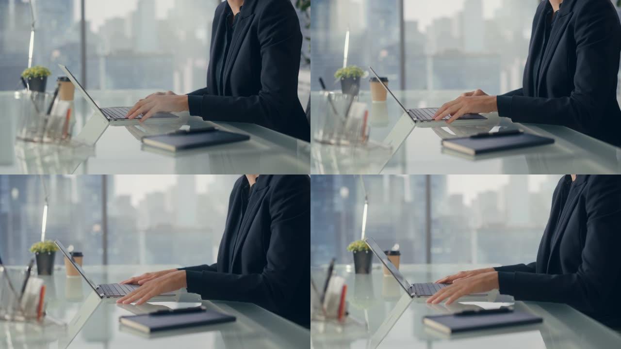 特写一位成功的女商人在笔记本电脑上工作的肖像，看着窗外的大城市。自信的女CEO分析金融项目。工作计划