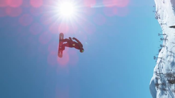垂直: 明亮的冬季阳光照在一名做后空翻的男性滑雪者身上。
