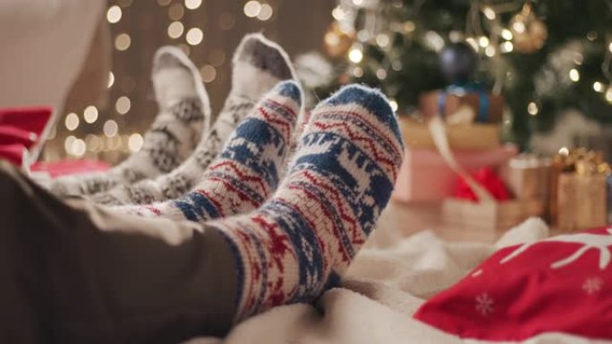 两个人坐在地板上的毯子上，穿着圣诞袜移动脚