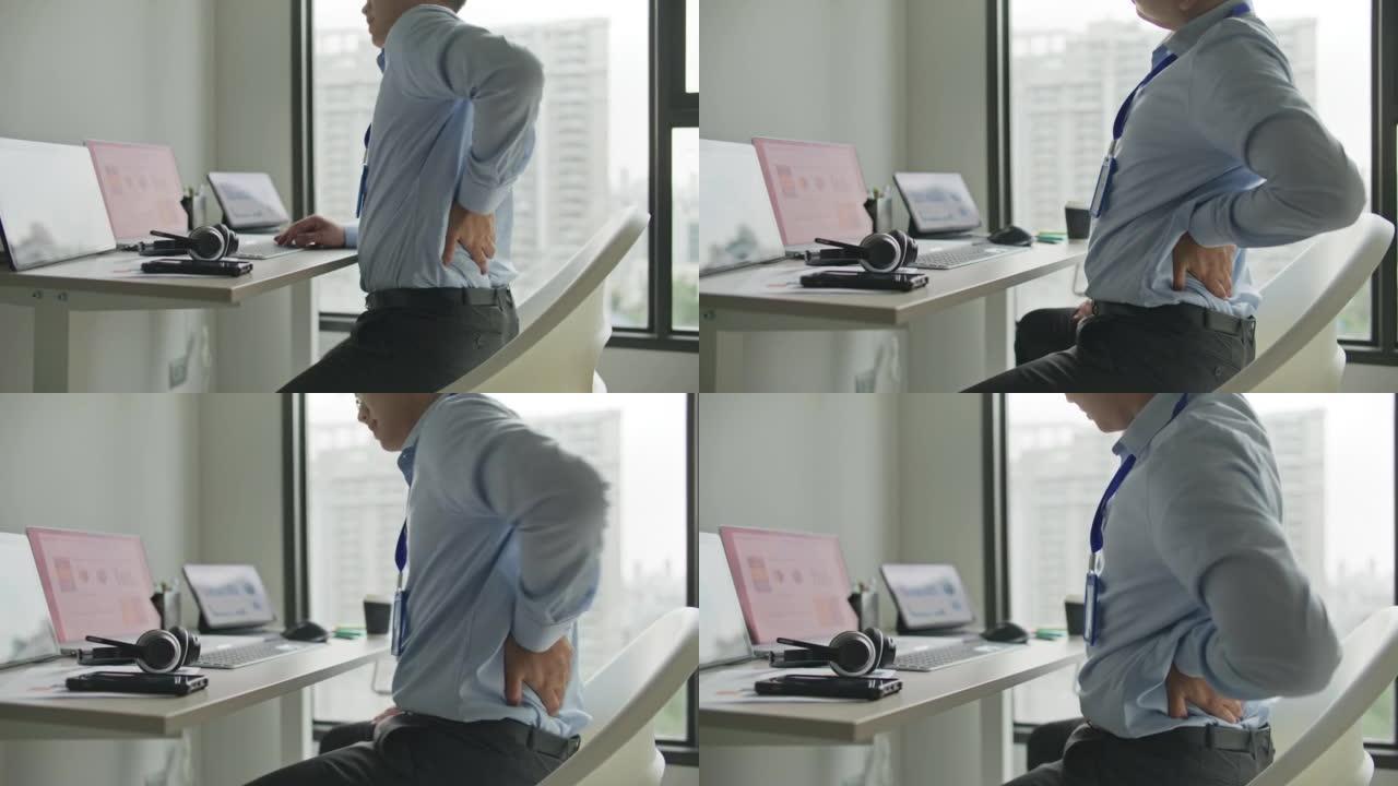 年轻的商人在办公室的办公桌上工作时背痛