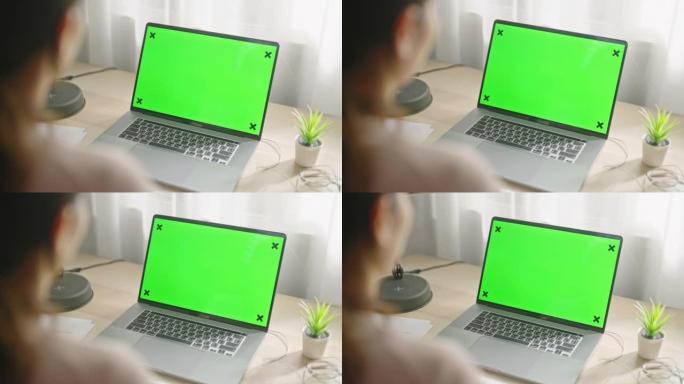 女人在家中使用带有绿屏的笔记本电脑