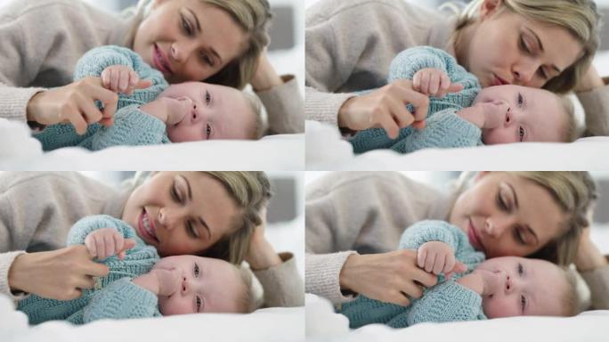 4k视频片段，一位年轻的母亲躺在床上与婴儿玩耍