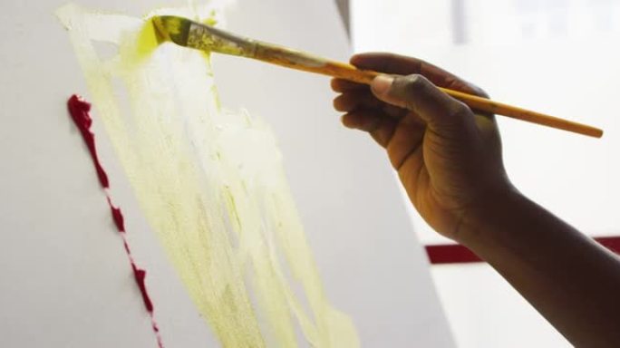 在艺术工作室，男画家在画布上绘画的手的特写