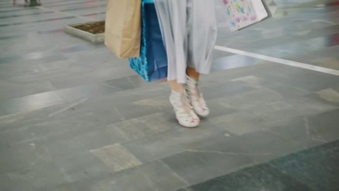 低矮的女人在购物中心提着购物袋