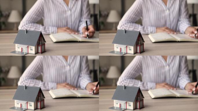 特写聚焦于站在桌子上的小房子模型。