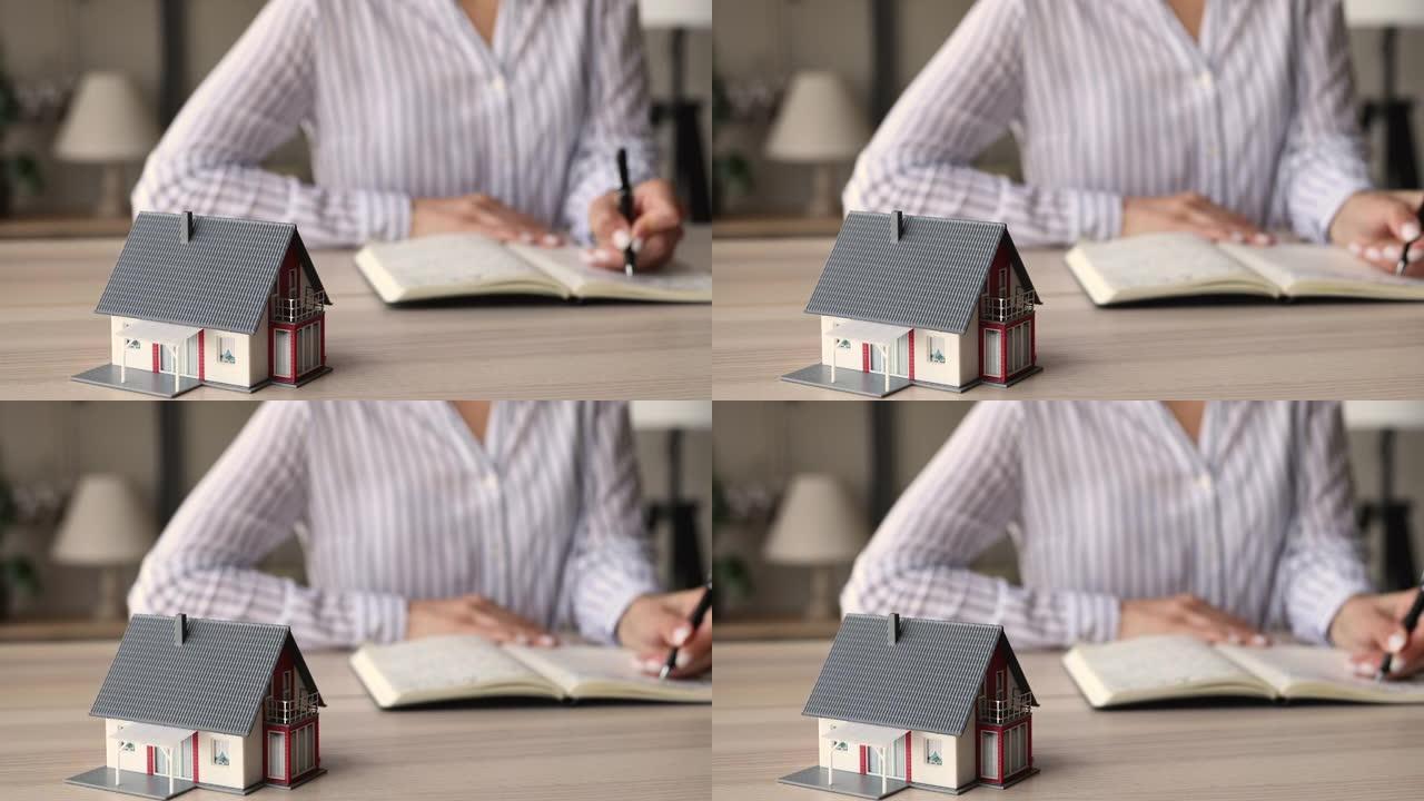 特写聚焦于站在桌子上的小房子模型。