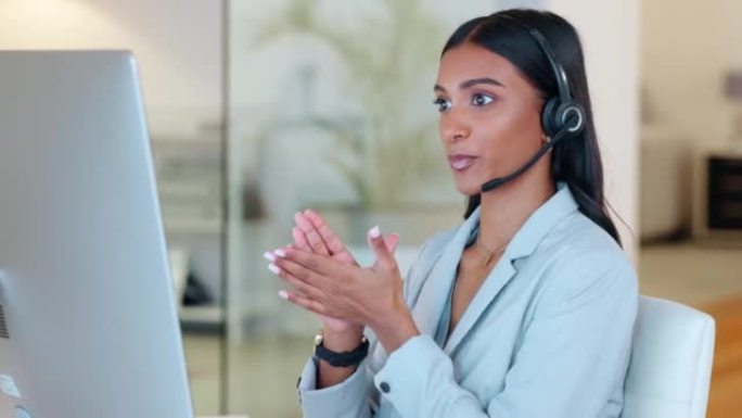 呼叫中心代理在办公室中独自在台式计算机上工作时与客户交谈并为其提供建议。年轻的印度客户服务代理戴着耳