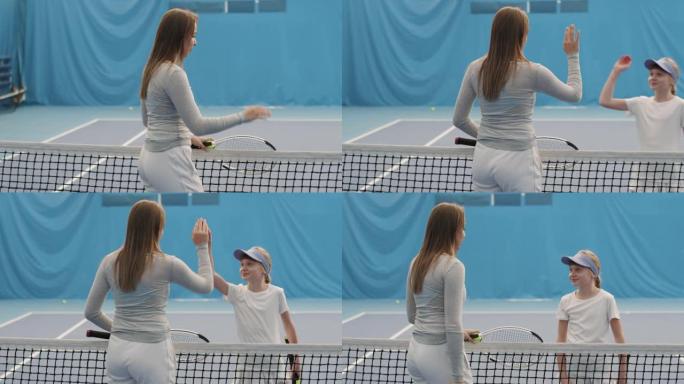 小女孩在球场上给网球教练高五