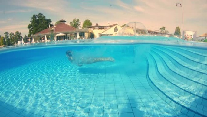 SLO MO在水下拍摄了一名女子跳入游泳池的镜头