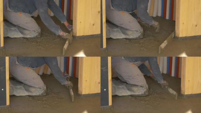 特写: 跪着承包商将覆盖地面的湿混凝土水平。