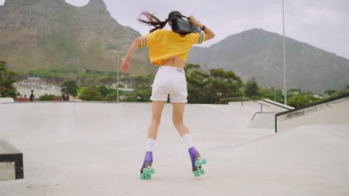 女轮滑运动员带着一个boombox在外面的滑板公园跳舞，旋转和向后走月球的乐趣。一个很酷的城市滑冰运