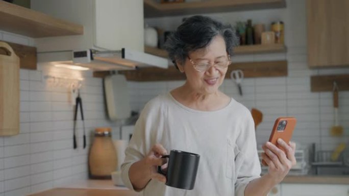 亚洲高级妇女手持咖啡杯与女儿进行视频通话。