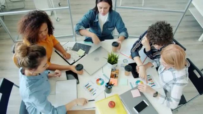 女性不同群体的高视角集思广益在办公室的餐桌上交谈和打手势