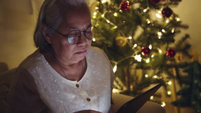 圣诞节期间在家观看数字平板电脑的高级女性。