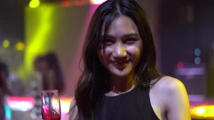 4k视频片段，一名亚洲年轻女性在夜总会跳舞时喝酒敬酒