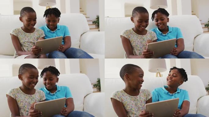 非裔美国男孩和女孩坐在家里的沙发上使用数字平板电脑