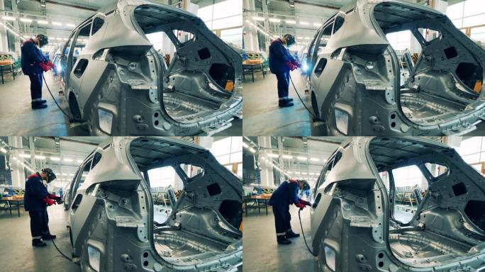 汽车厂工人正在焊接未完工汽车的车身