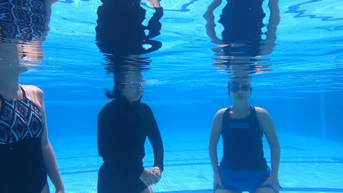 亚洲华人游泳在游泳池里练习在水下呼吸，用鼻子吹空气