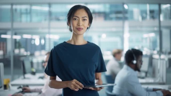 成功的女商人穿着时髦的衣服，使用平板电脑，站在现代多元化的办公室从事金融、商业和营销项目。美丽的亚洲