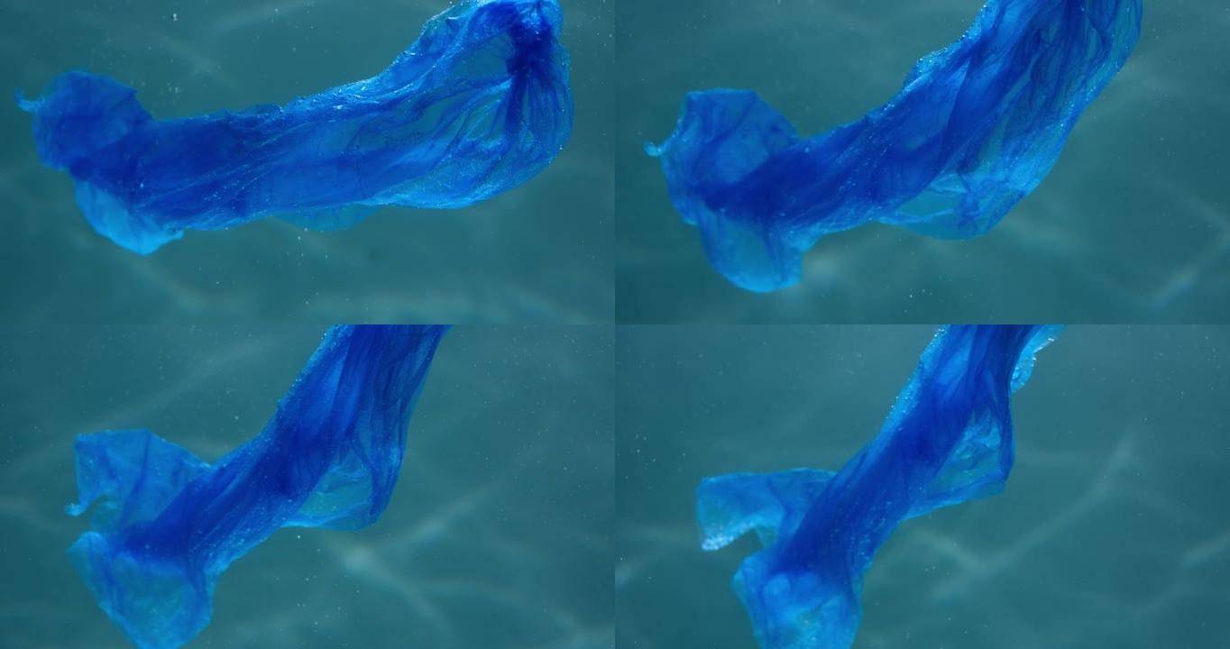 被塑料污染的海洋。特写蓝色一次性袋在光线背景下漂浮在水下慢动作。