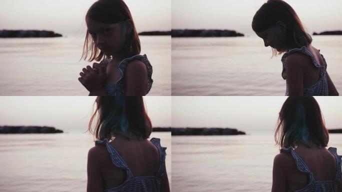 可爱的高加索少女在平静的金色日出海边的剪影肖像，转身观看风景慢动作。