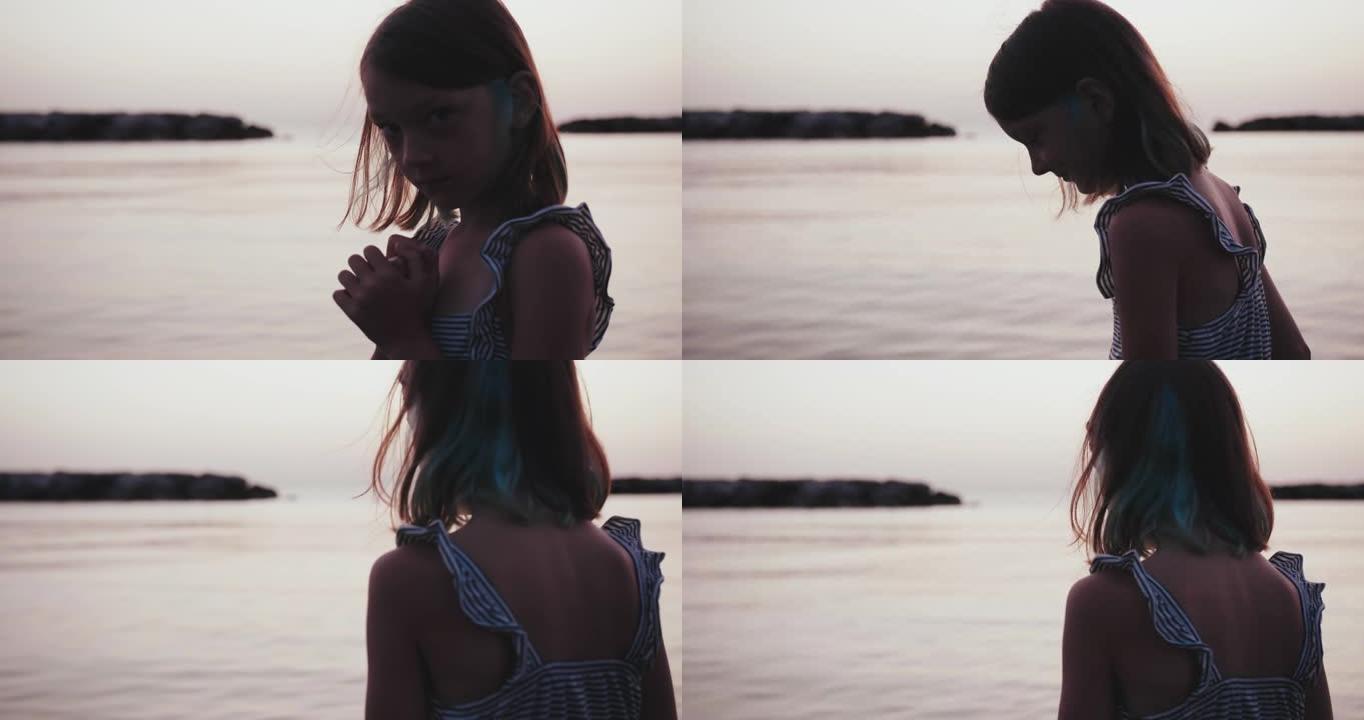可爱的高加索少女在平静的金色日出海边的剪影肖像，转身观看风景慢动作。