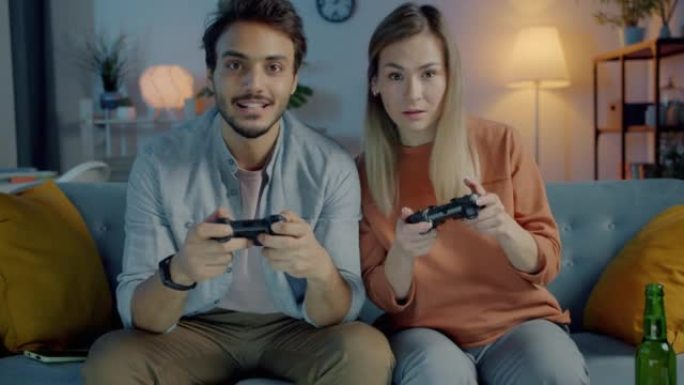 快乐的年轻夫妇玩电子游戏晚上在家一起玩