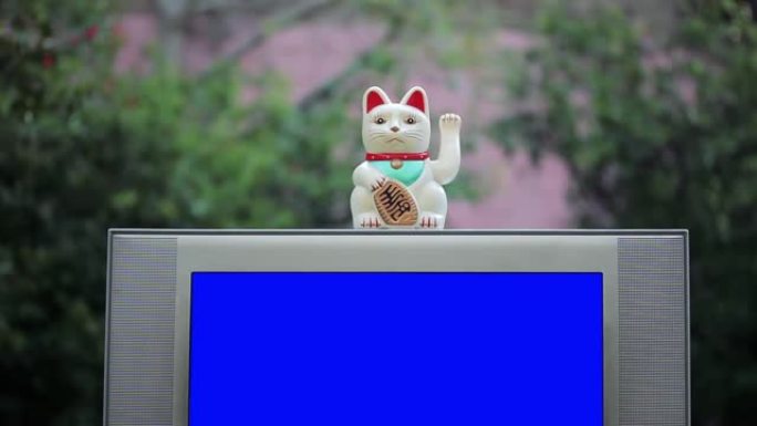 Maneki Neko幸运猫和带蓝屏的旧电视。