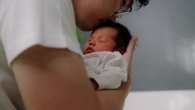 父亲用手在家里的托儿所里背着新生的男婴。陪产假
