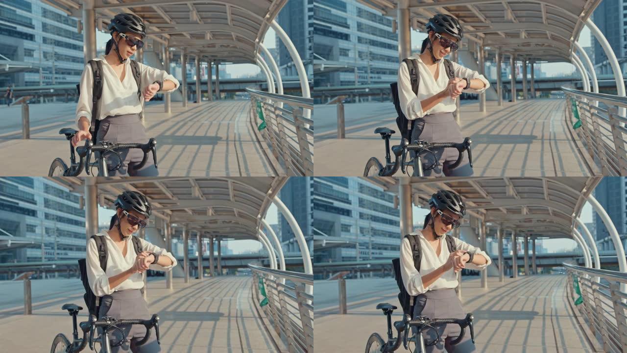 亚洲女商人带着背包自行车微笑看城市街道的智能手表去办公室上班。