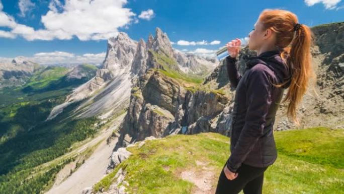 女游客从山上徒步旅行中休息，在令人叹为观止的地方用水瓶喝水