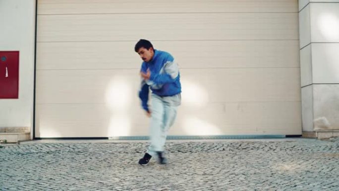 在城市的城市环境中，活跃而开朗的年轻拉丁男人穿着时髦的衣服，在一个大车库门前积极跳舞嘻哈。在一个小镇