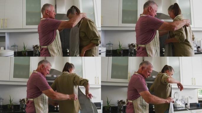 高加索高级男子帮助妻子在家里的厨房里穿上围裙