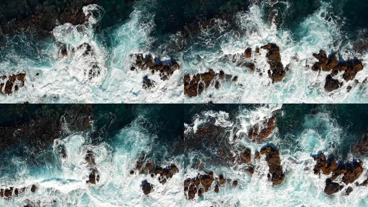 暴风雨期间的岩石海岸。绿松石色透明海水在岩石上挥动和撞击。许多飞溅和泡沫。空中自上而下拍摄，4K