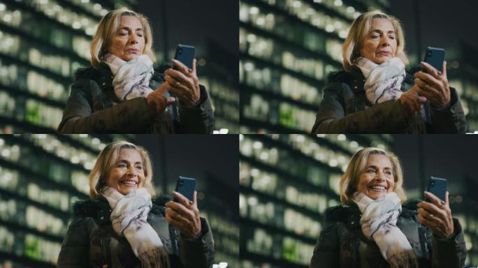 一位迷人的高级女性晚上在市中心使用手机。