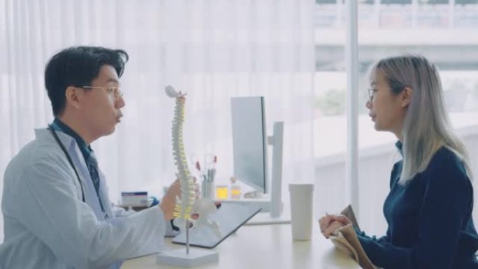 亚洲男医生向病人展示解剖脊柱。