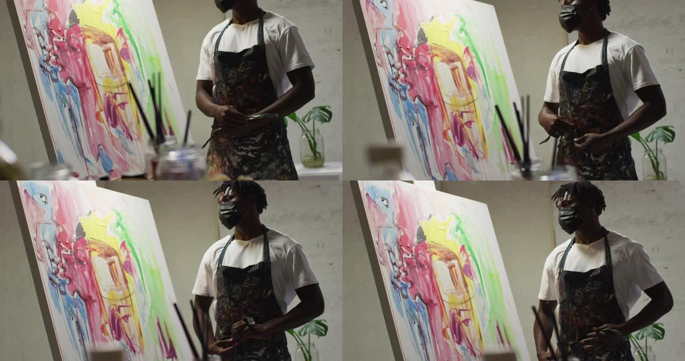 非裔美国男艺术家戴着口罩在艺术工作室系围裙